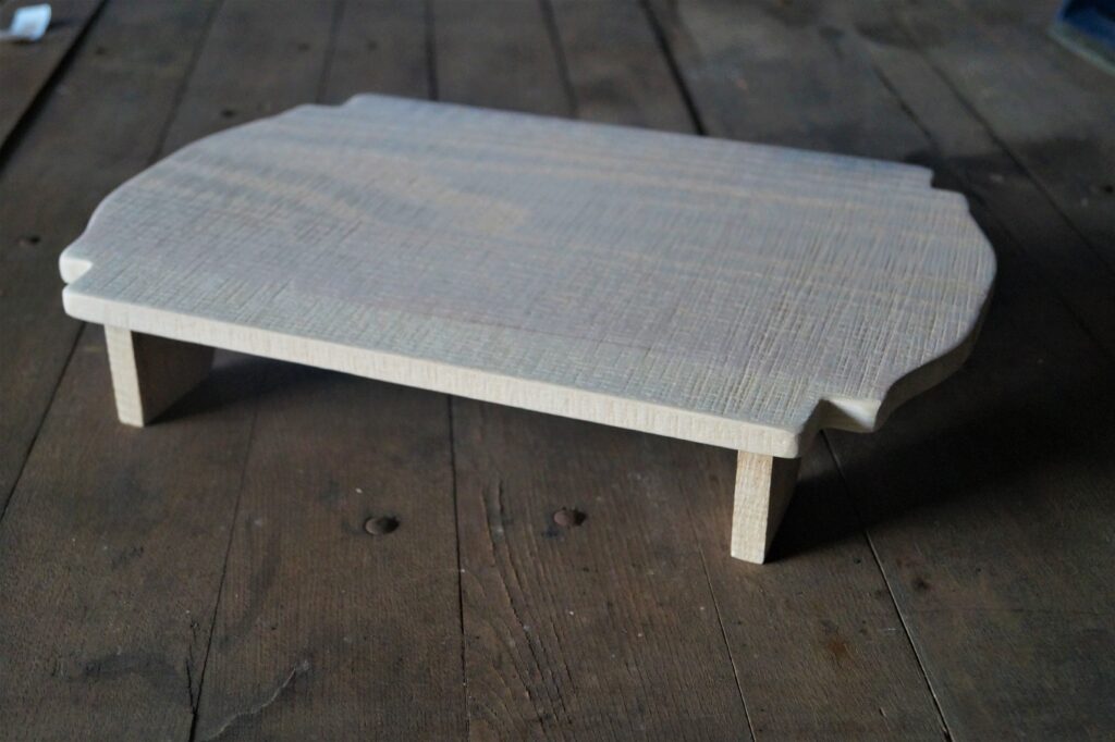 footed wood serving board with scalloped edges.