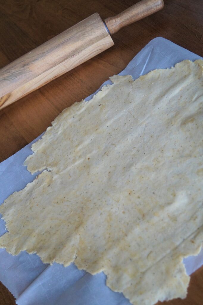 cracker dough rolled out with wooden rolling pin 