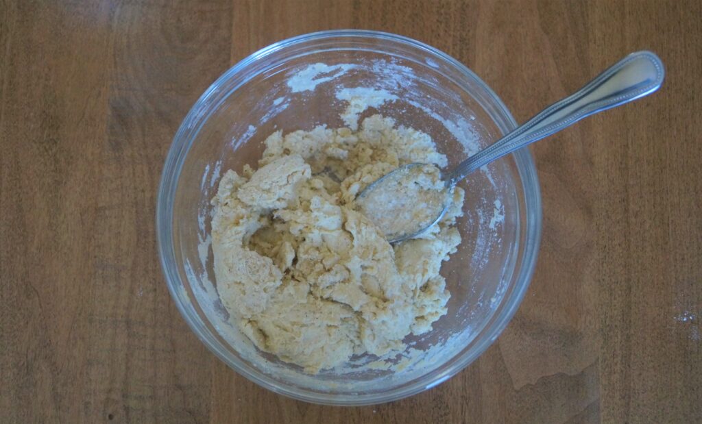 shaggy rosemary parmesan sourdough dough mixed with a spoon 