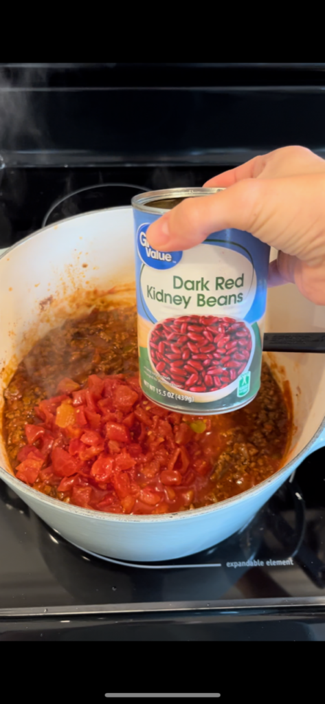 kidney beans held above pot of chili 