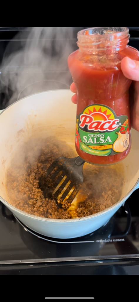 salsa held above light blue pot on stovetop 