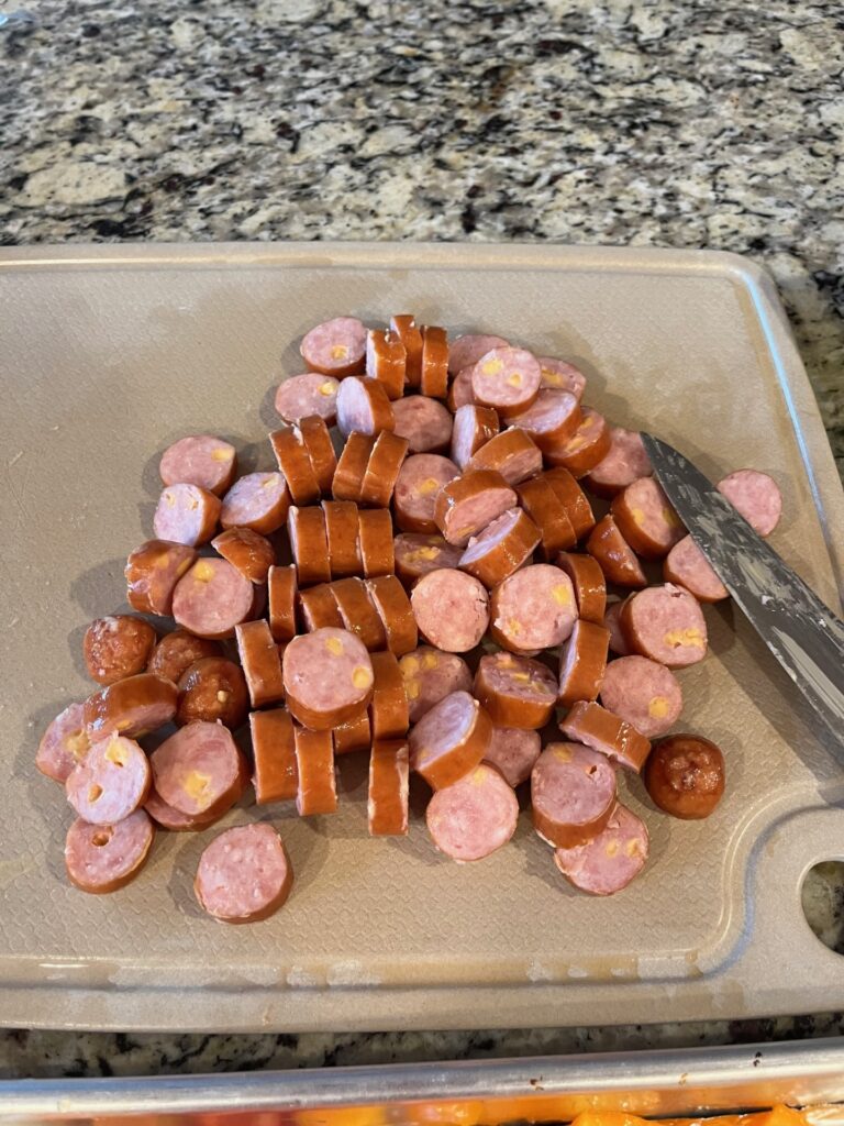 cheesy sausage cut up on cutting board 