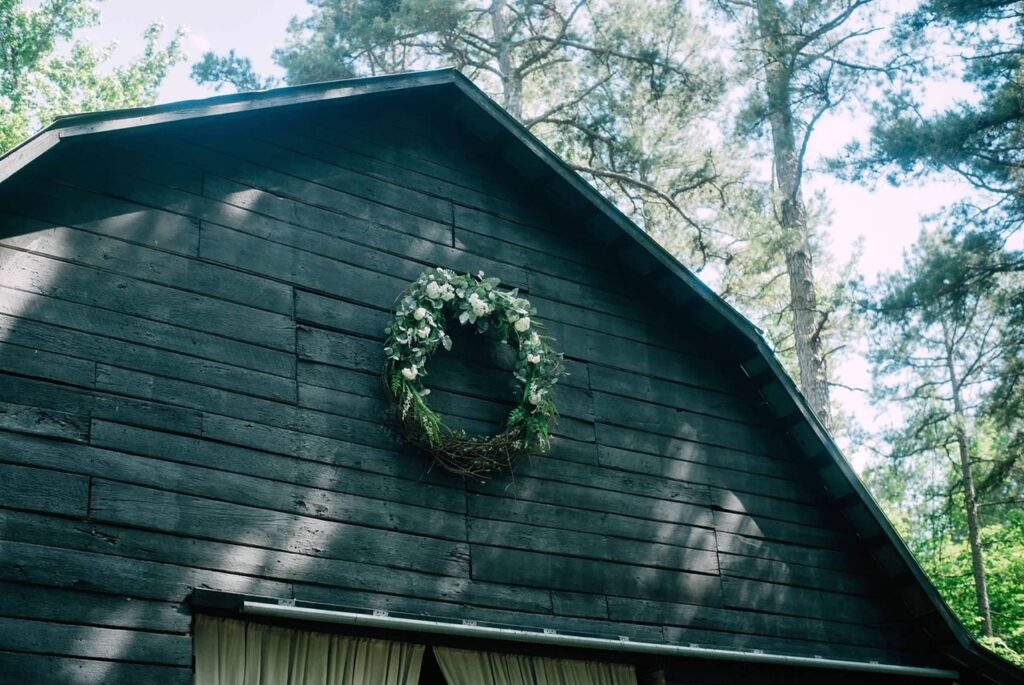 giant wreath hanging on front of wedding barn