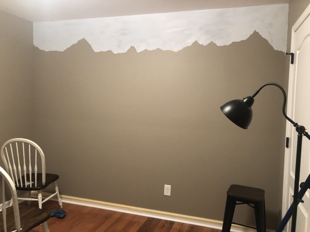 light blue paint at top of wall outlining first mountain 