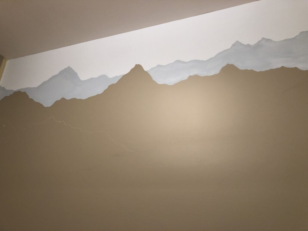 light blue paint and slightly darker blue paint outlining two mountain ranges 